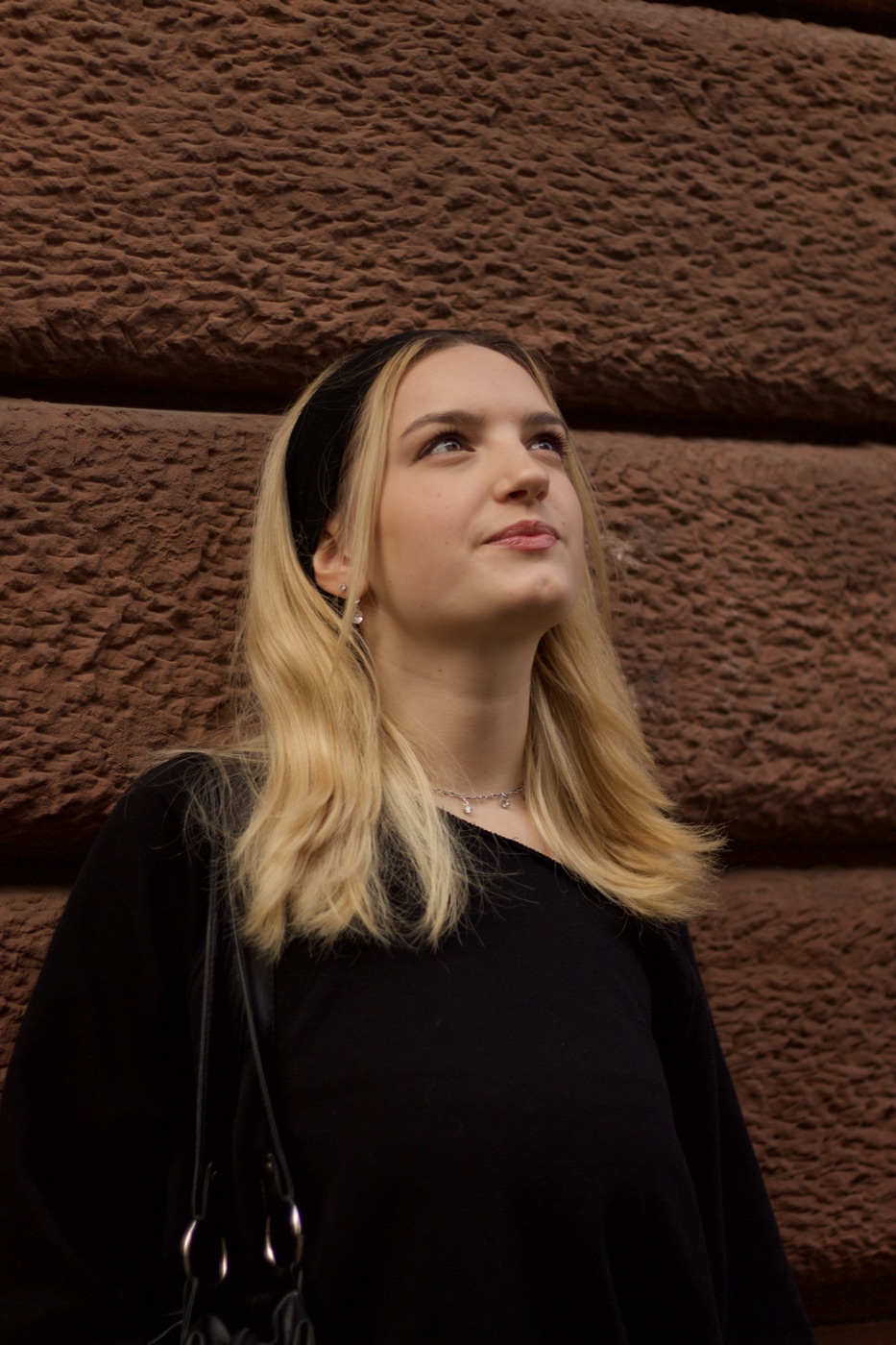 Outdoor portrait against a textured red wall.